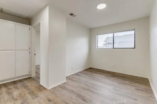 a view of an empty room with wooden floor and closet