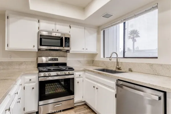 a kitchen with granite countertop a stove a microwave a sink and cabinets