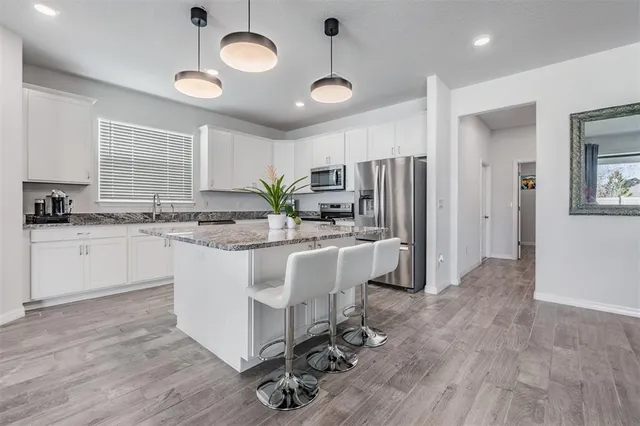 a kitchen with stainless steel appliances granite countertop a stove top oven a sink dishwasher a dining table and chairs with wooden floor