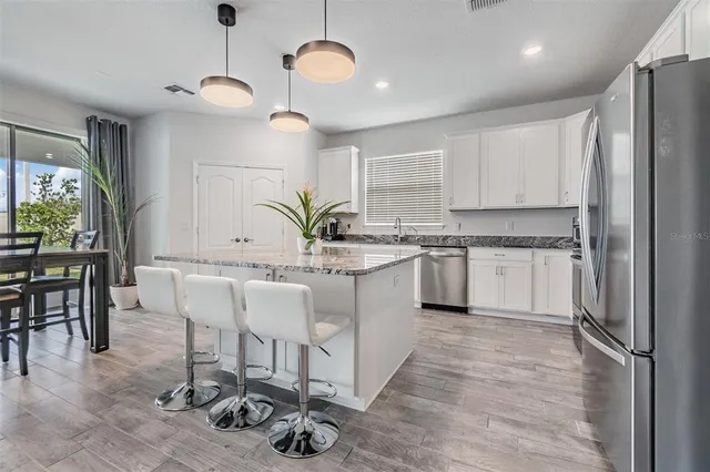 a kitchen with kitchen island granite countertop a sink cabinets and wooden floor