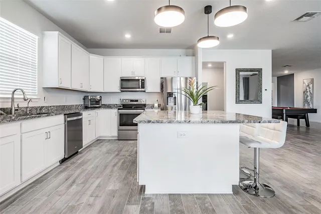 a kitchen with stainless steel appliances kitchen island granite countertop a stove and a sink
