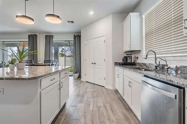 a kitchen with stainless steel appliances granite countertop a refrigerator a stove top oven a sink and dishwasher with wooden floor