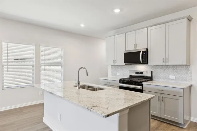 a kitchen with a sink a refrigerator and a stove top oven