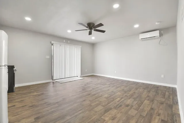 an empty room with wooden floor ceiling fan and windows