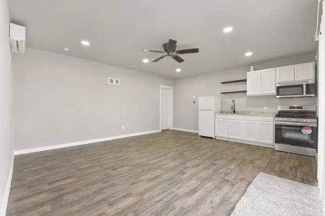 a view of a kitchen with a sink and dishwasher a stove top oven with wooden floor