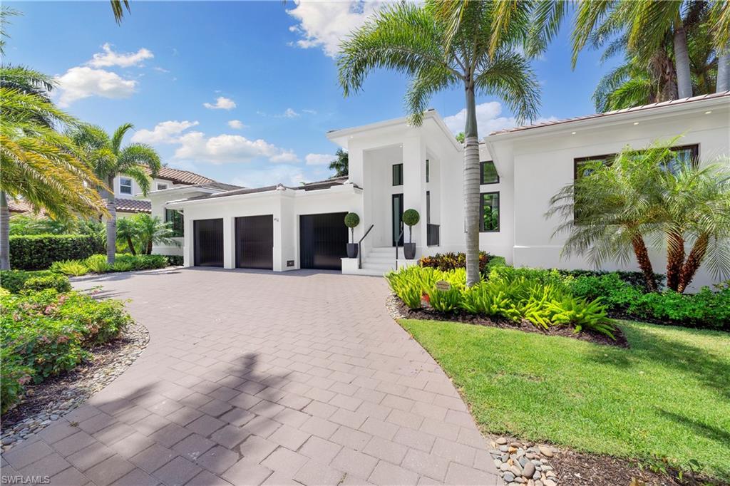 a front view of a house with a garden and palm trees