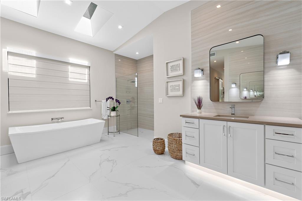 470 Wedge Drive Naples, FL 34103 - Photo 18 of 28 a spacious bathroom with a double vanity sink a mirror a bathtub and next to a window