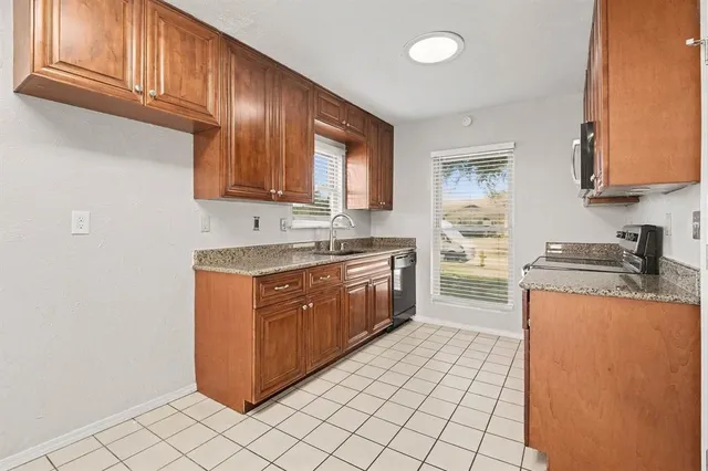 a kitchen with stainless steel appliances granite countertop a stove a sink and a refrigerator