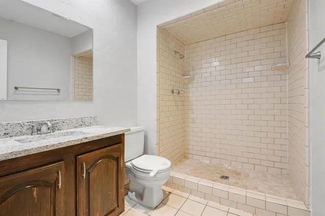 a bathroom with a granite countertop sink a toilet and shower