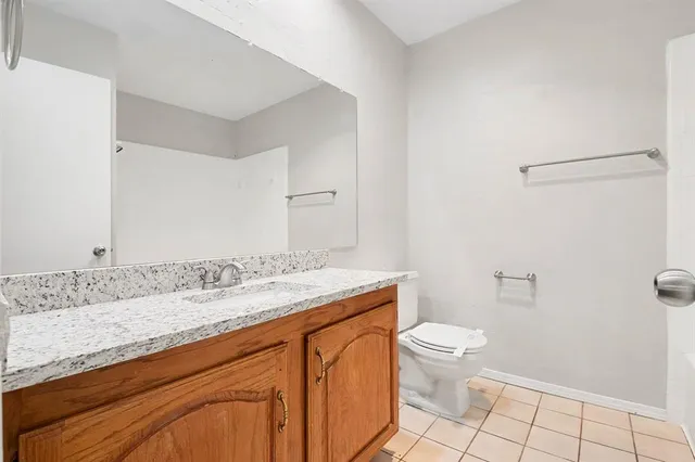 a bathroom with a granite countertop sink a toilet and a mirror