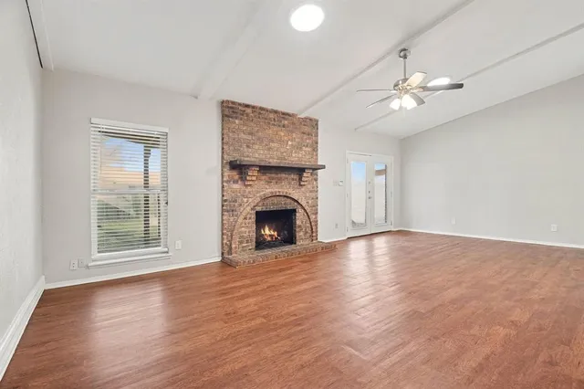 an empty room with windows fireplace and wooden floor
