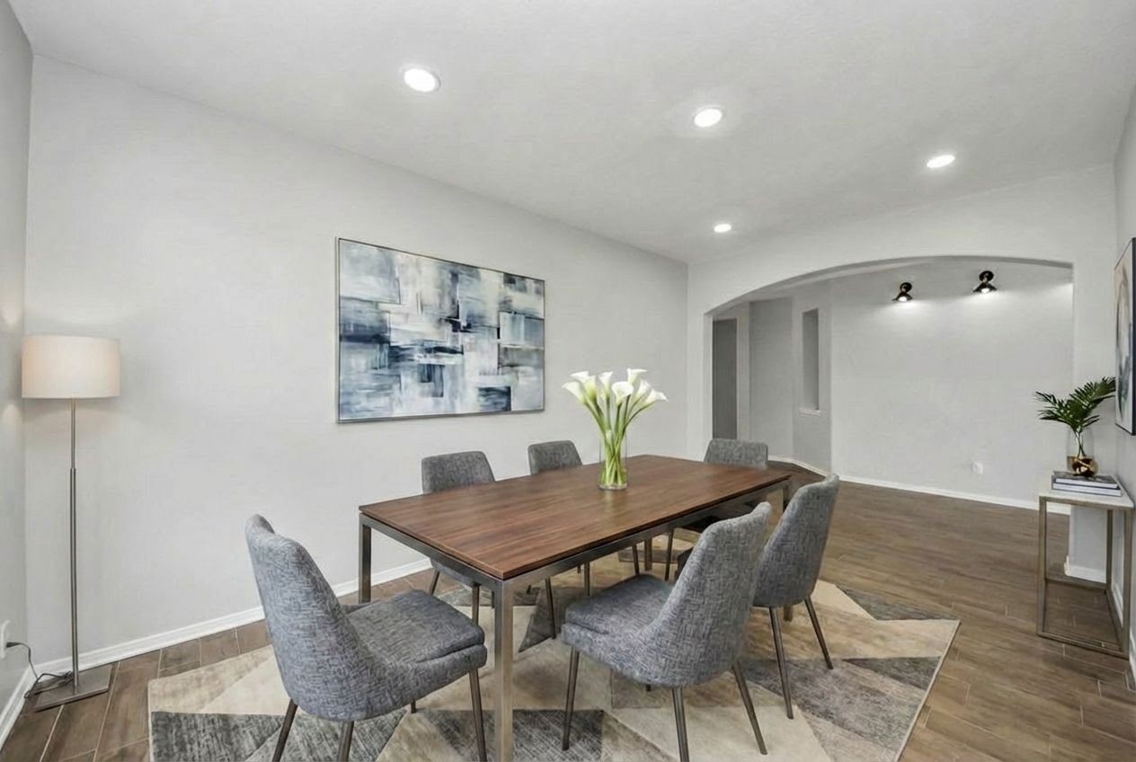 2306 2 Trail Drive Spring, TX 77373 - Photo 12 of 27 Modern dining room with a sleek wooden table and six upholstered chairs. The space is bright with brand new recessed lighting, neutral walls, and a large abstract painting.
