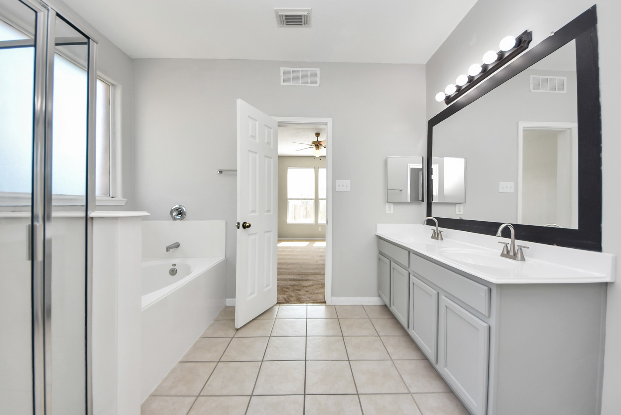 2306 2 Trail Drive Spring, TX 77373 - Photo 16 of 27 Bright and spacious bathroom featuring a large mirror, dual sinks, and a modern vanity. It includes a separate shower, a bathtub.