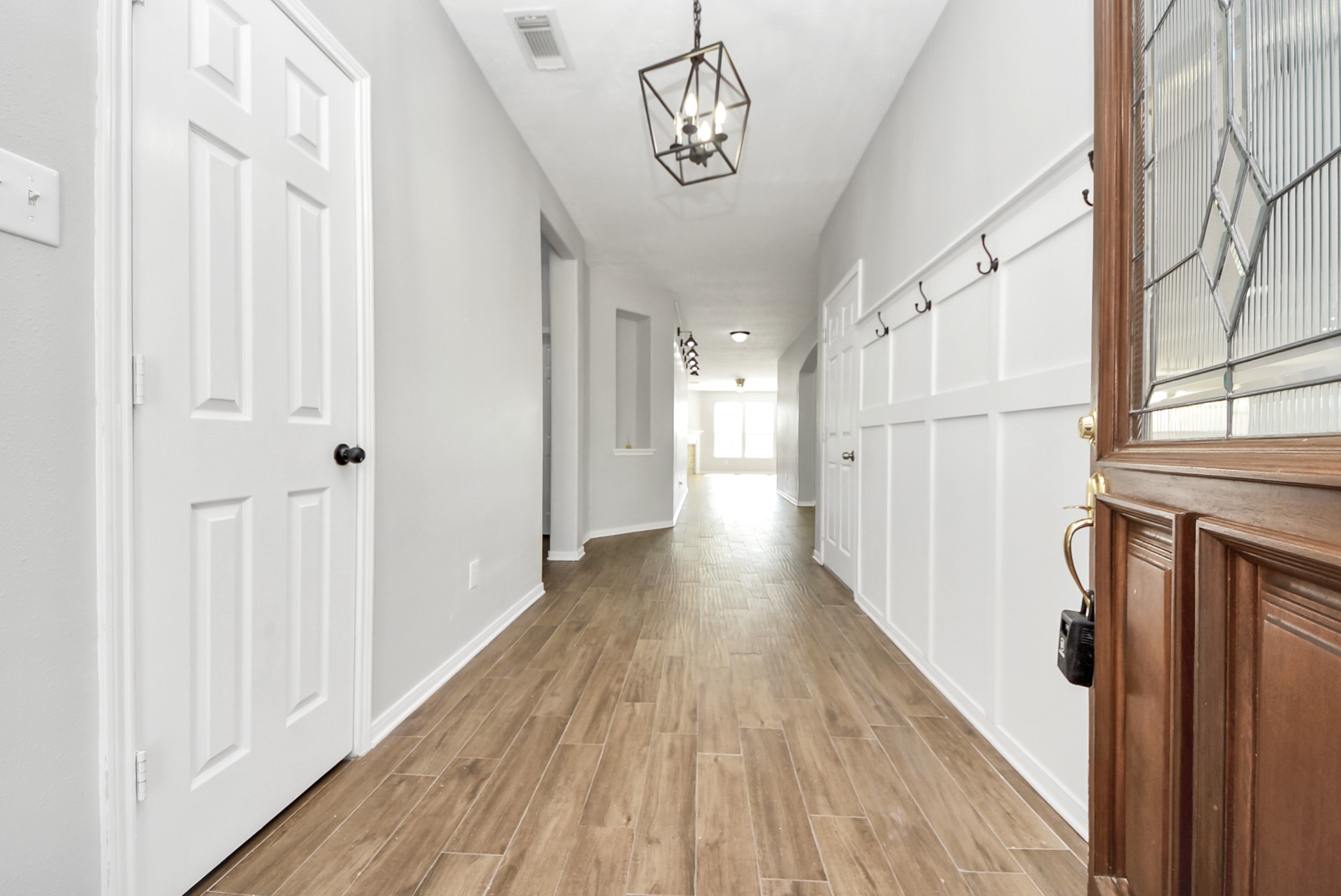 2306 2 Trail Drive Spring, TX 77373 - Photo 2 of 27 Bright and welcoming entryway with wood-style flooring, modern lighting, and white paneled walls.