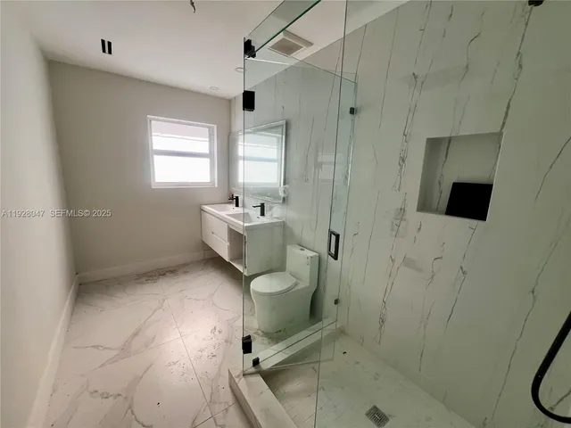 a bathroom with a granite countertop sink toilet and shower