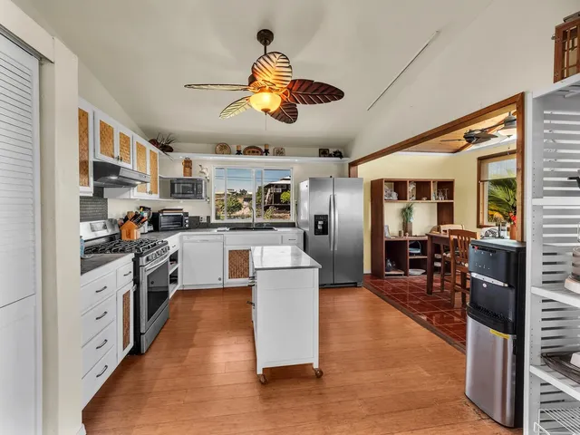 a kitchen with stainless steel appliances granite countertop a lot of cabinets and wooden floor