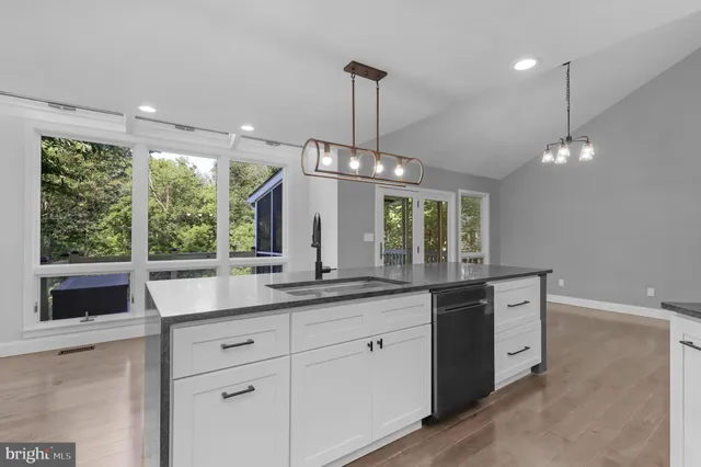 a view of a kitchen with kitchen island wooden floor and stainless steel appliances
