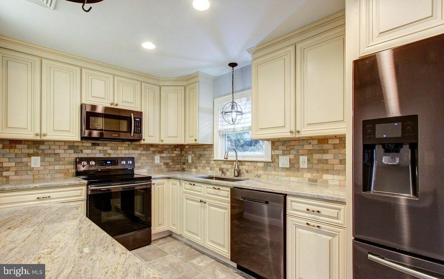 a kitchen with granite countertop a refrigerator stove and microwave