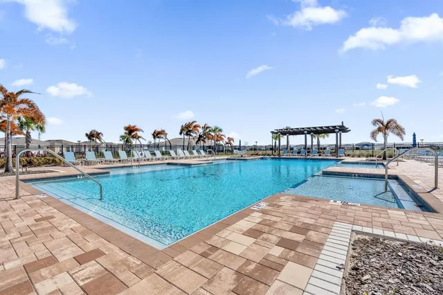a view of a swimming pool with a lawn chairs under an umbrella