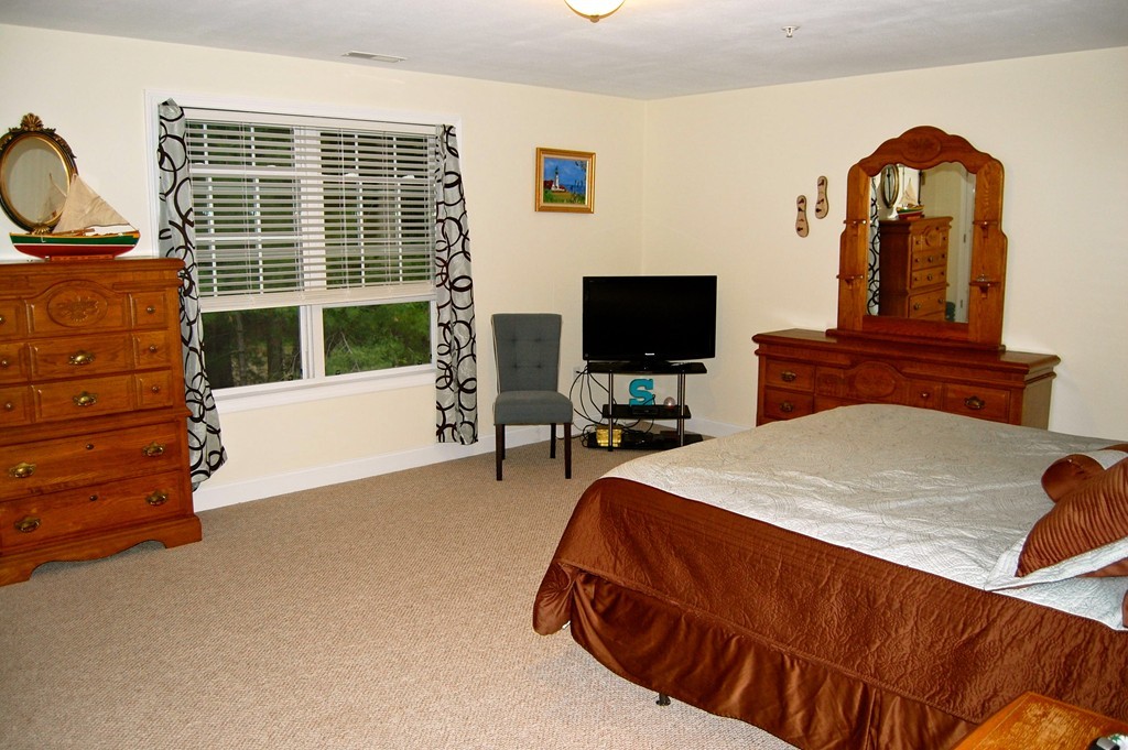 90 Rangeway Road, Unit 104 Billerica, MA 01862 - Photo 8 of 8 a bedroom with a bed and a flat tv screen on dresser