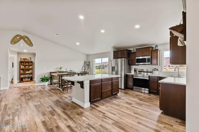 a large kitchen with stainless steel appliances kitchen island granite countertop a refrigerator and a stove top oven