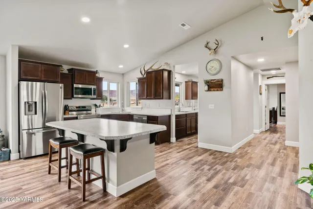 a kitchen with stainless steel appliances granite countertop a sink stove microwave and refrigerator