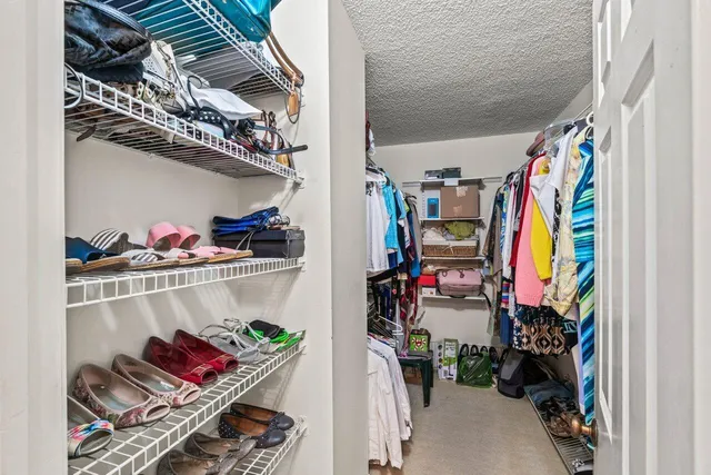 a view of walk in closet with clothes and shoes