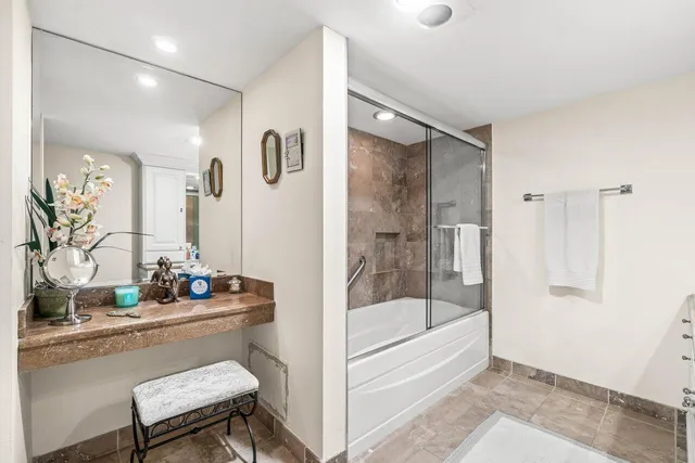 a bathroom with a tub shower sink and mirror