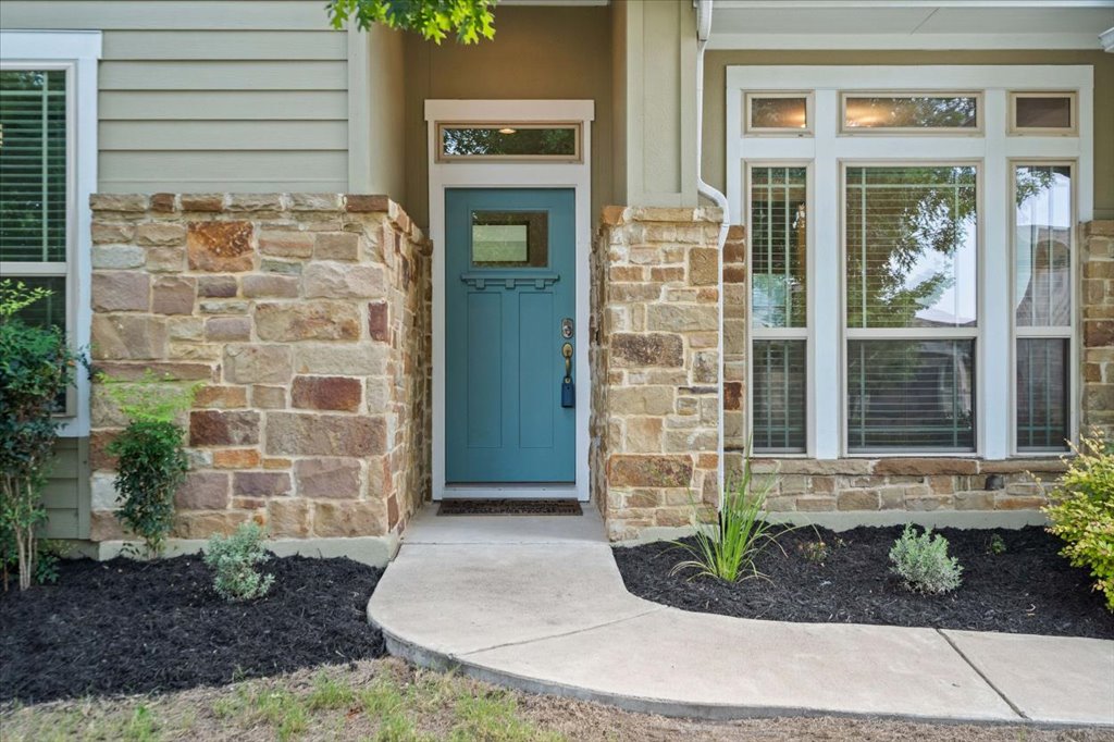Stone accents and a curved concrete walkway frame the welcoming front entry.
