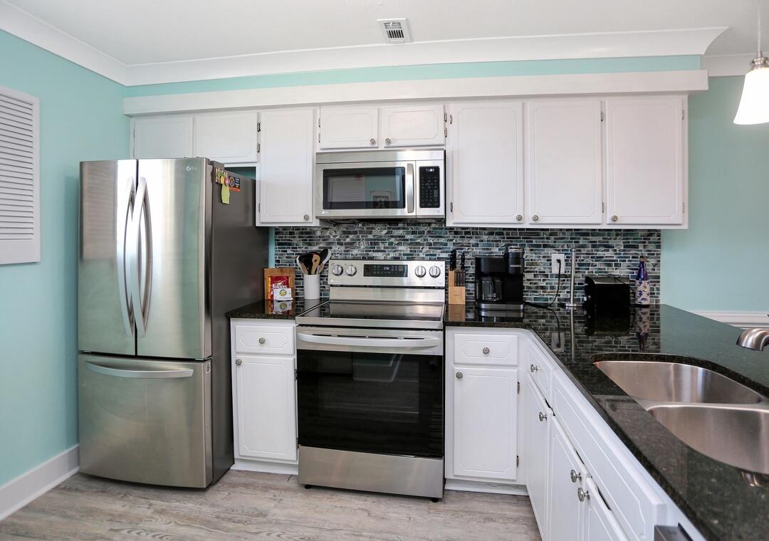 3869 Cape San Blas Road Port St. Joe, FL 32456 - Photo 43 of 52 a kitchen with stainless steel appliances granite countertop a refrigerator a stove a sink and a microwave