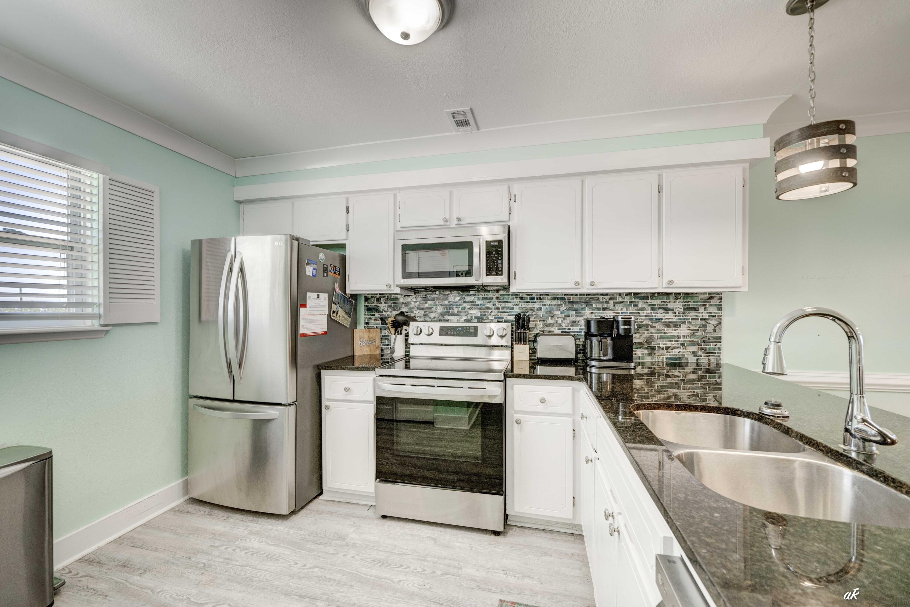 3869 Cape San Blas Road Port St. Joe, FL 32456 - Photo 5 of 52 a kitchen with stainless steel appliances granite countertop a refrigerator a stove a sink and a microwave