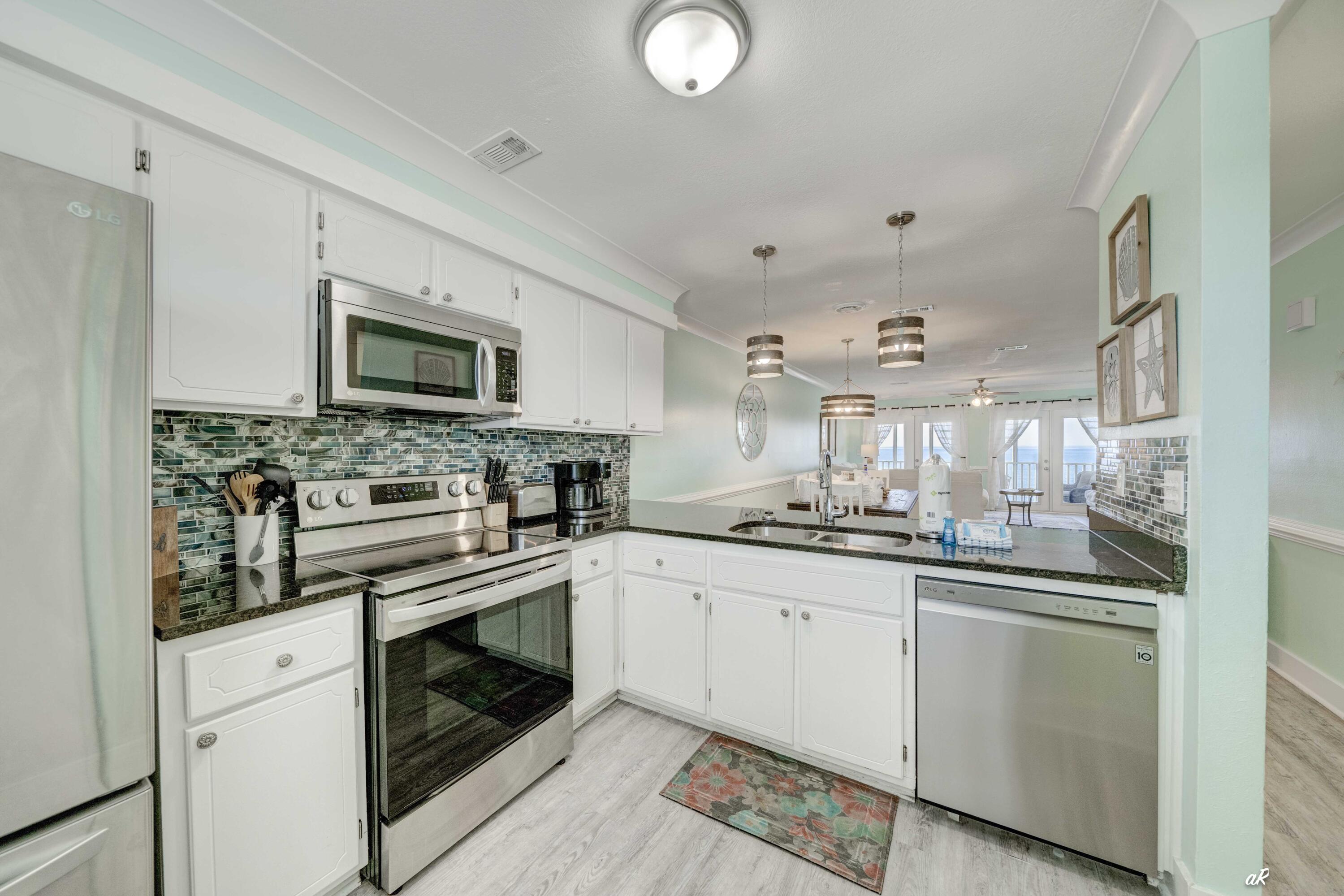 3869 Cape San Blas Road Port St. Joe, FL 32456 - Photo 8 of 52 a kitchen with granite countertop a sink stainless steel appliances and white cabinets