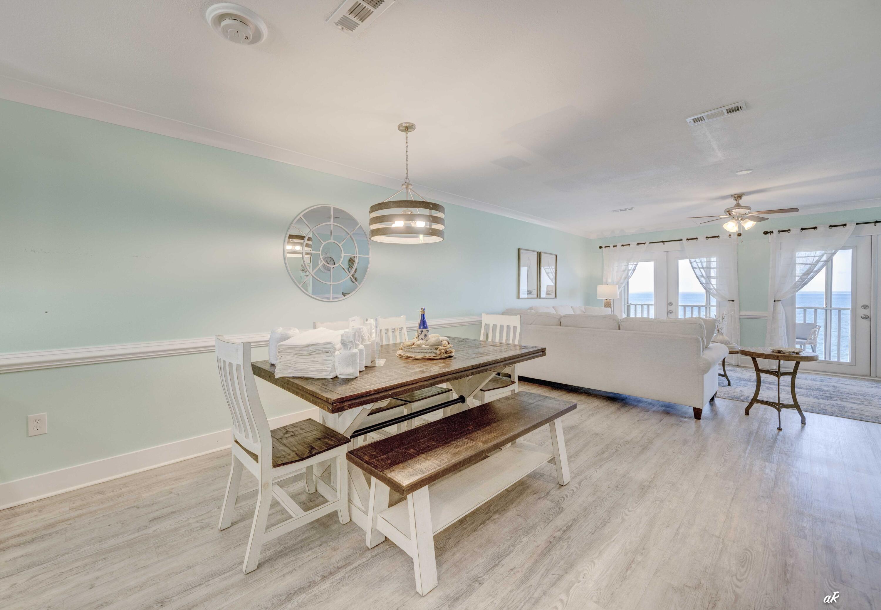 3869 Cape San Blas Road Port St. Joe, FL 32456 - Photo 10 of 52 a dining room with wooden floor a chandelier a wooden table and chairs
