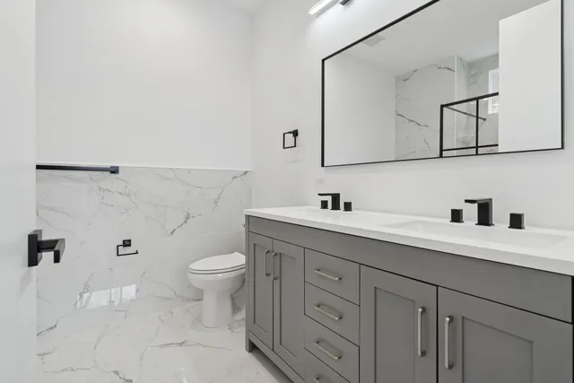 a bathroom with a double vanity sink toilet and mirror