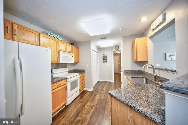 a kitchen with granite countertop a sink stove and refrigerator
