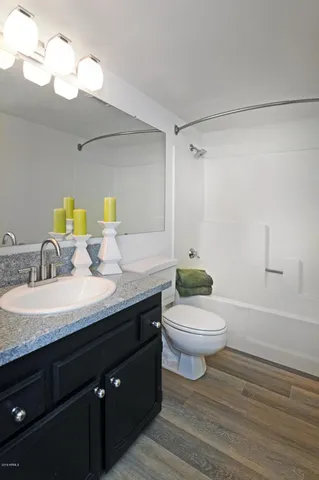 a bathroom with a granite countertop toilet sink and mirror