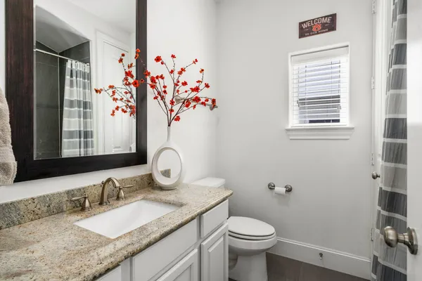 a bathroom with a granite countertop sink mirror vanity and toilet
