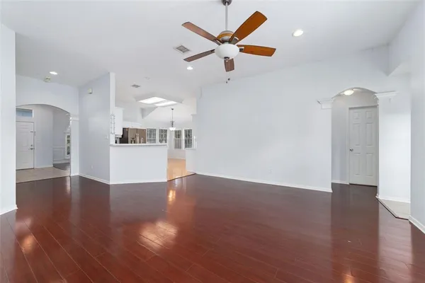 a view of empty room with wooden floor and ceiling fan