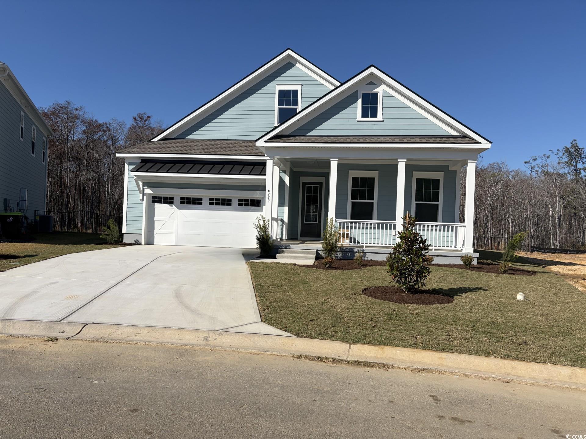 6779 Genesis Drive Murrells Inlet, SC 29576 - Photo 1 of 1 View of front facade with a shingled roof, a front yard, a porch, and driveway