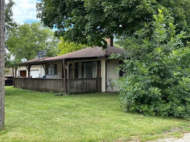 a view of a house with a yard and a large tree