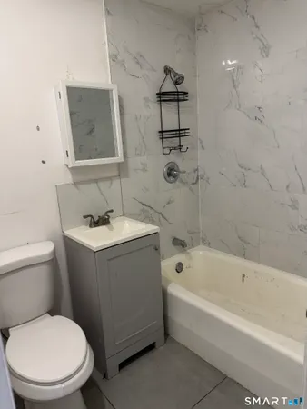 a white toilet sitting next to a bath tub
