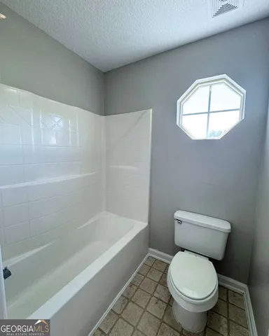 a white toilet sitting next to a bath tub and a shower