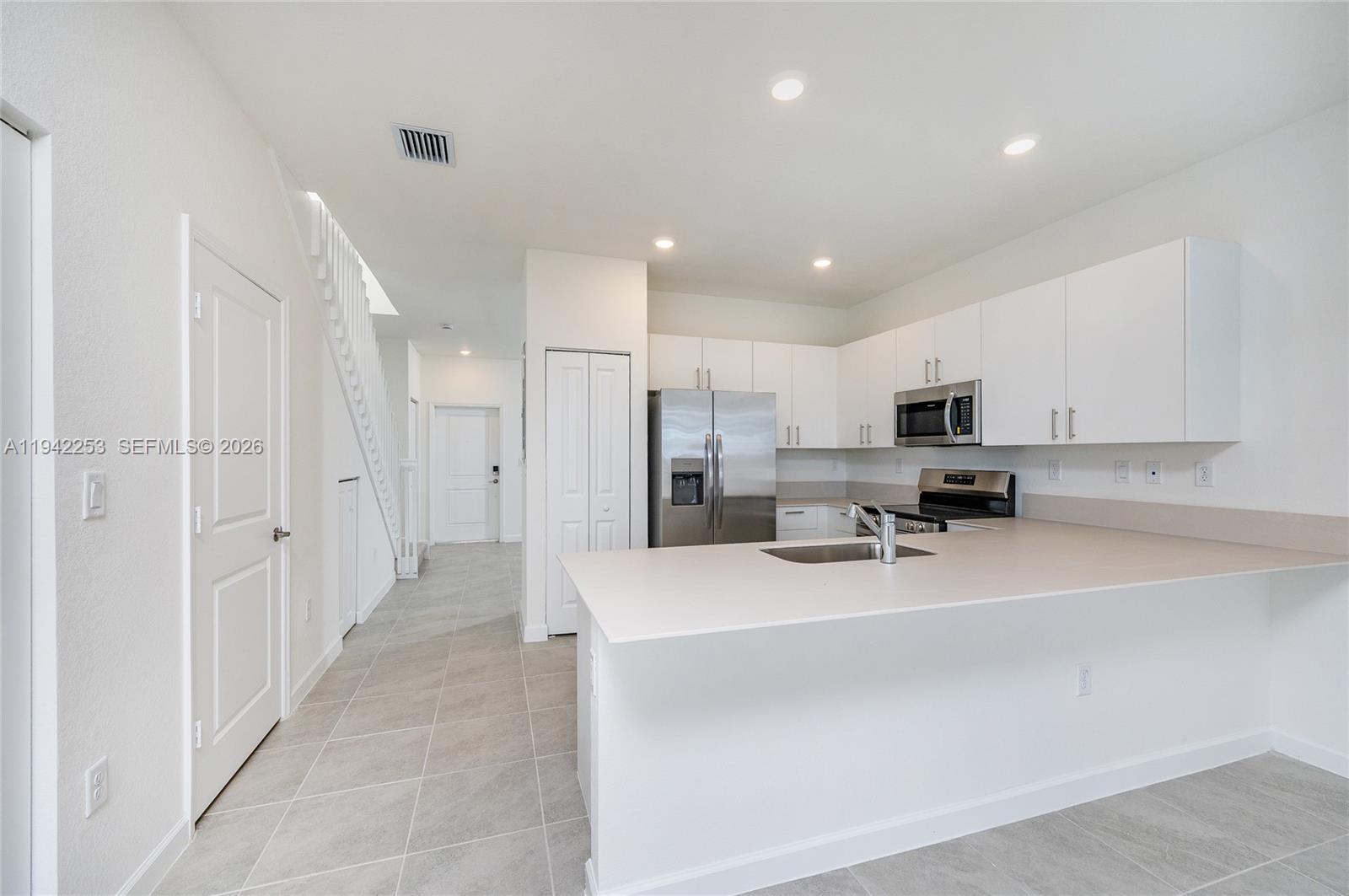 2747 Southeast 26th Road, Unit 2747 Homestead, FL 33035 - Photo 9 of 27 a kitchen with stainless steel appliances a refrigerator sink stove microwave and cabinets