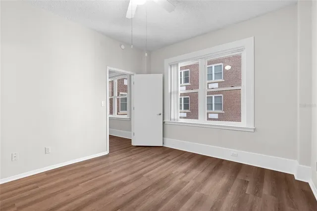 a view of an empty room with wooden floor and a window