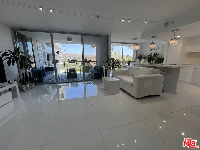 a living room with furniture kitchen view and a large window