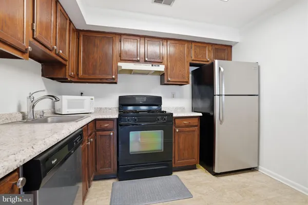 a kitchen with stainless steel appliances granite countertop a refrigerator stove a sink and dishwasher with wooden floor