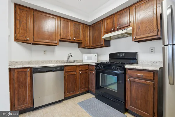 a kitchen with stainless steel appliances granite countertop wooden cabinets a stove top oven a sink and dishwasher