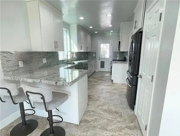 a kitchen with stainless steel appliances granite countertop a refrigerator and a stove top oven