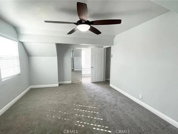 an empty room with a ceiling fan and carpet