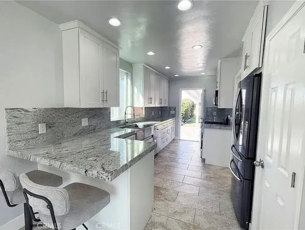 a kitchen with stainless steel appliances granite countertop a sink refrigerator and cabinets
